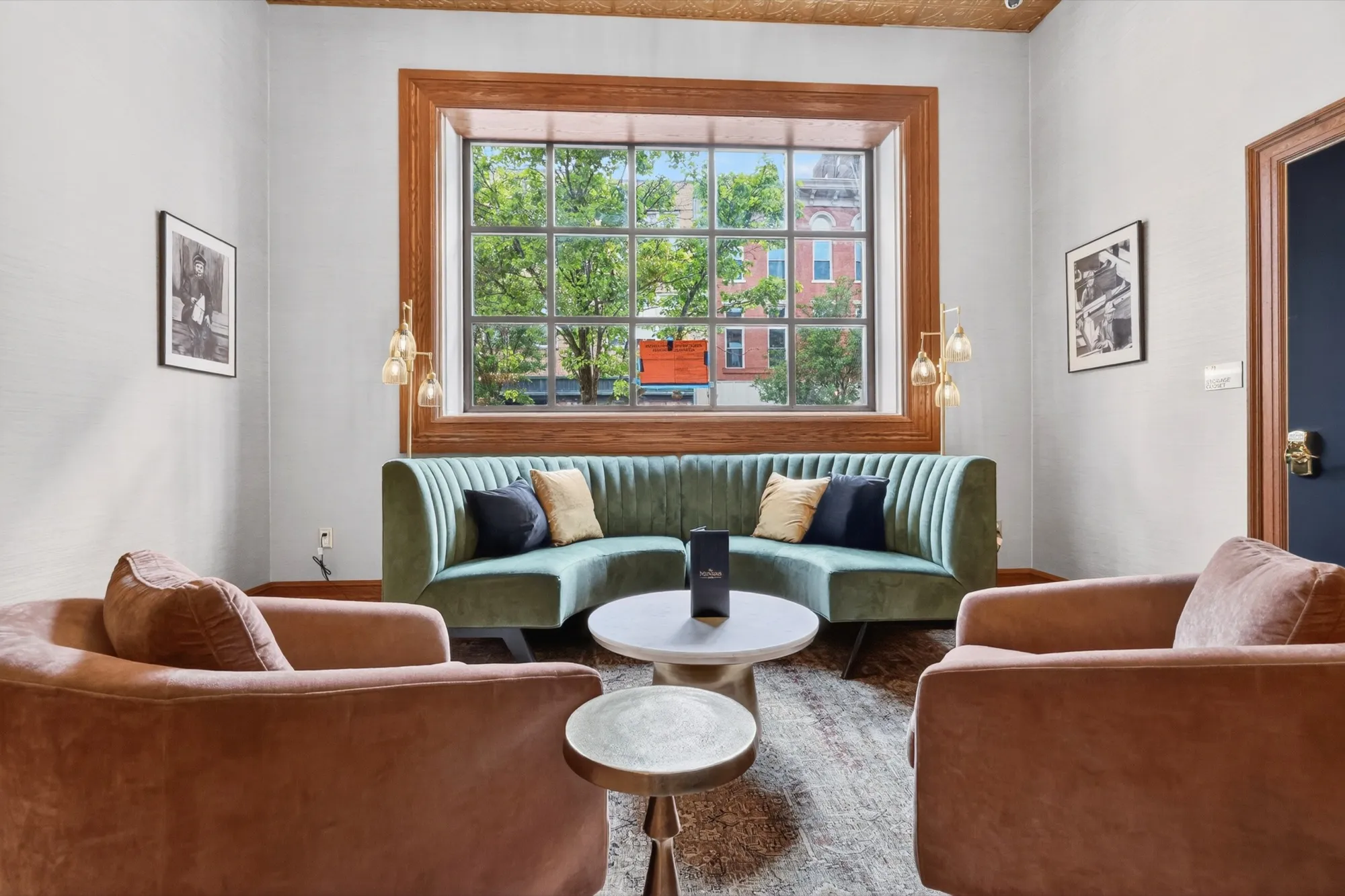 A cozy café seating nook with a green velvet sofa and armchairs by a sunny window
