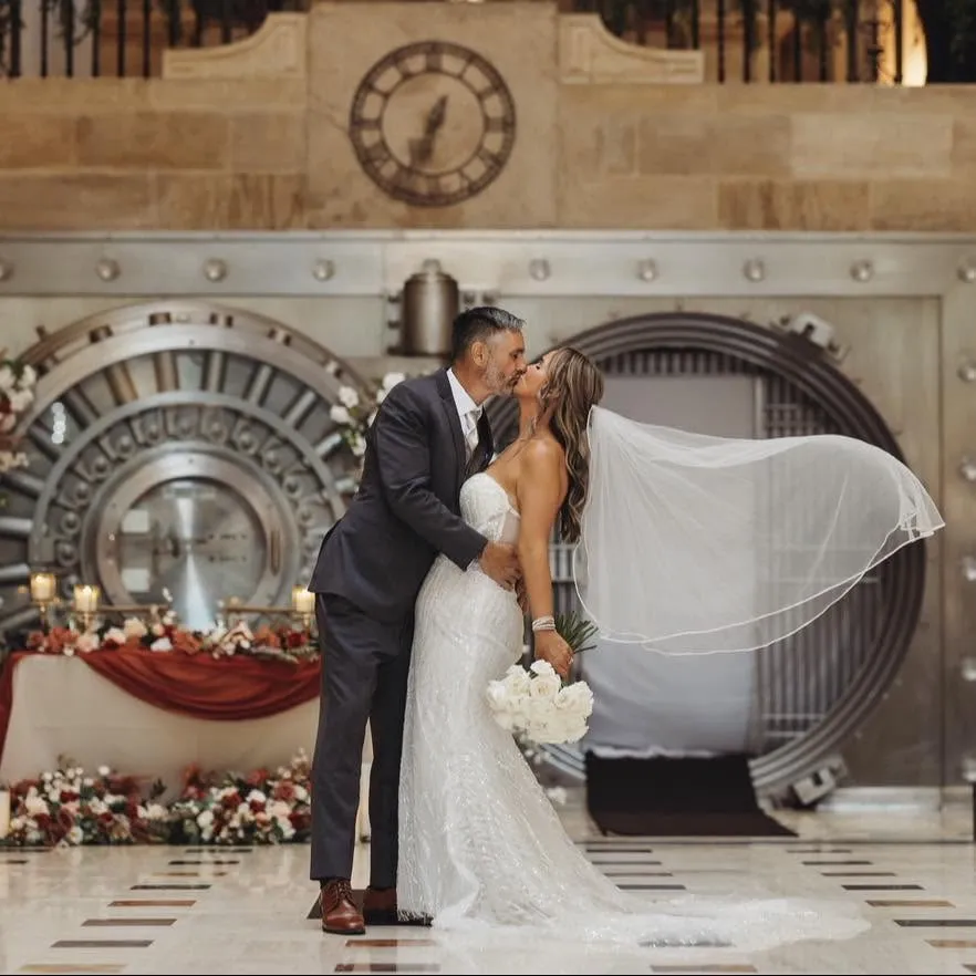 Bride and groom kissing in front of a large historic bank vault.