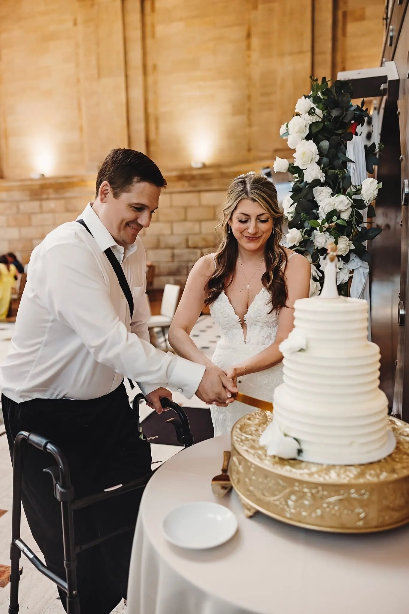 A newlywed couple cutting their tiered wedding cake beside the historic vault at The Miners 1928