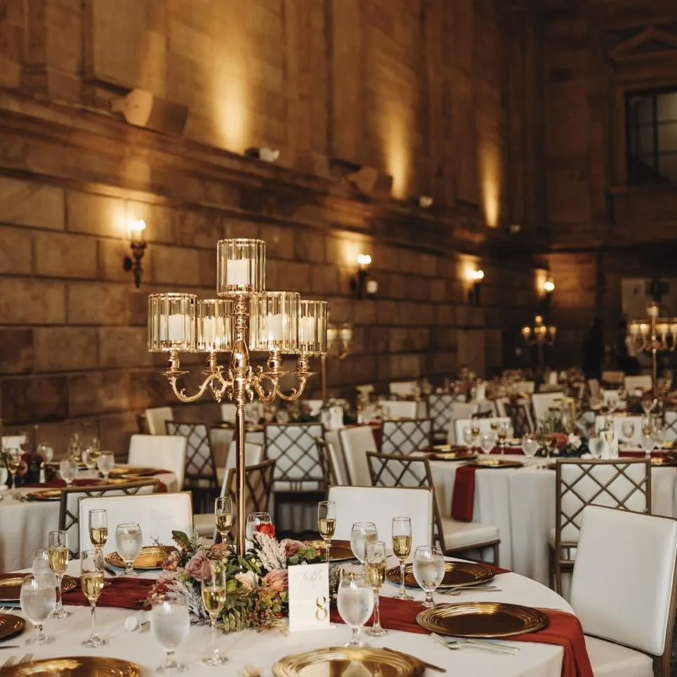 Wedding reception table setup with a gold candelabra centerpiece and red runner.